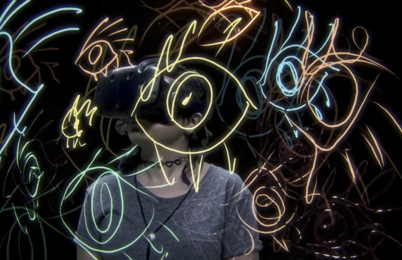 A women wearing VR headset and infront of her there is colourful drawings.